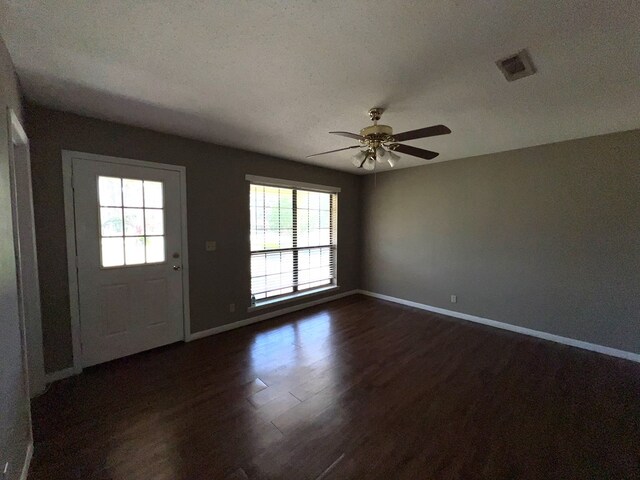 interior space with dark wood-style floors, plenty of natural light, a ceiling fan, and visible vents