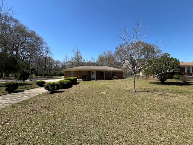 view of front of property featuring brick siding, a front lawn, and driveway