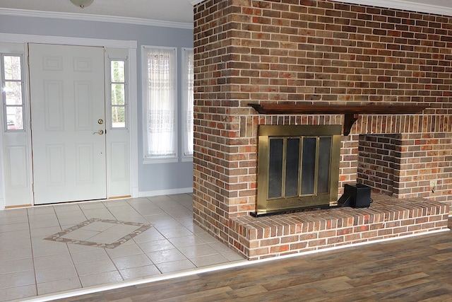 tiled entrance foyer with crown molding, a healthy amount of sunlight, and baseboards