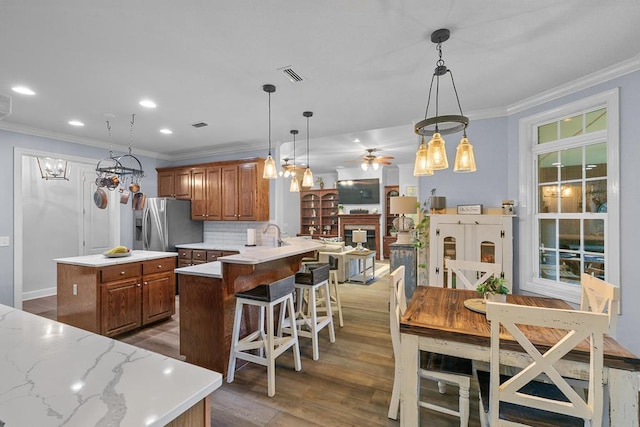 306 Halifax Dr, Dothan, AL 36305 - kitchen with brown cabinets, crown molding, light wood-type flooring, hanging light fixtures, and a kitchen island
