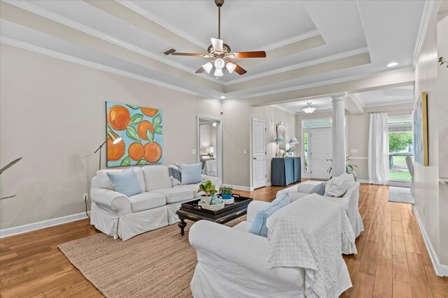 living room featuring light wood-type flooring, ornate columns, a ceiling fan, and baseboards