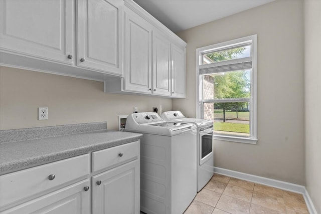 clothes washing area featuring baseboards, washer and dryer, and cabinet space