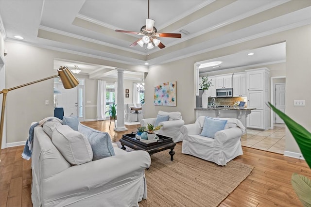 living room featuring ornate columns, ornamental molding, ceiling fan, and light wood-style flooring