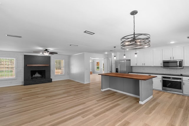 1005 Rampart Dr, Dothan, AL 36303 - kitchen with appliances with stainless steel finishes, butcher block countertops, white cabinetry, open floor plan, and a brick fireplace