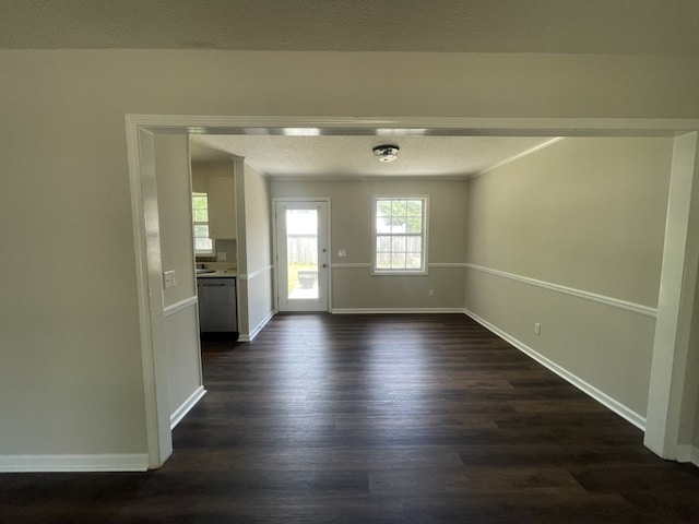 unfurnished dining area with dark wood finished floors, baseboards, and a textured ceiling