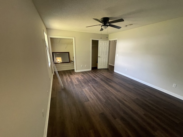unfurnished bedroom with dark wood-style floors, baseboards, a textured ceiling, and ceiling fan