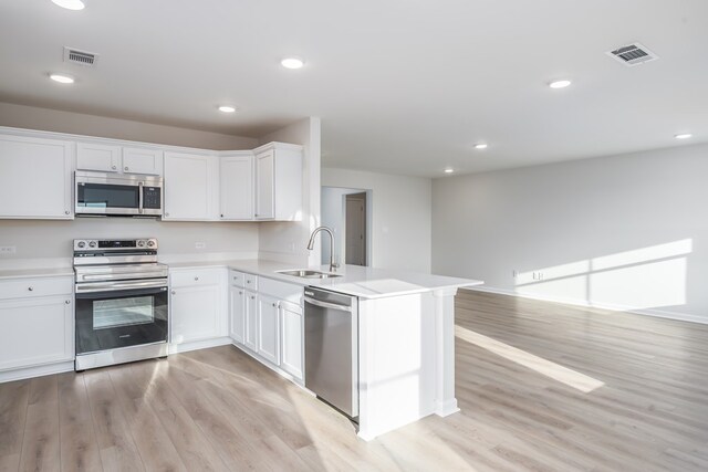 1017 Sandbed Rd, Newton, AL 36352 - kitchen with stainless steel appliances, light wood-style floors, light countertops, a peninsula, and white cabinets