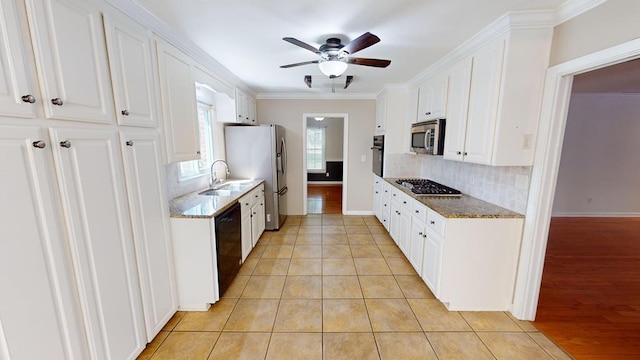 kitchen featuring light wood-type flooring, dark stone counters, crown molding, black appliances, and white cabinets