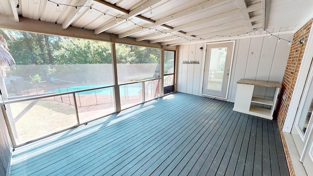 unfurnished sunroom featuring a healthy amount of sunlight and beam ceiling