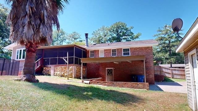 rear view of property with a lawn and a sunroom