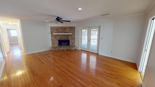 unfurnished living room with plenty of natural light, light wood-type flooring, ornamental molding, and french doors