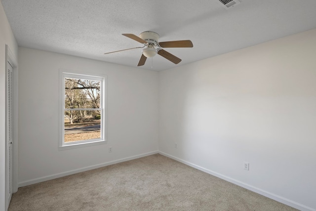 carpeted spare room featuring ceiling fan and a textured ceiling