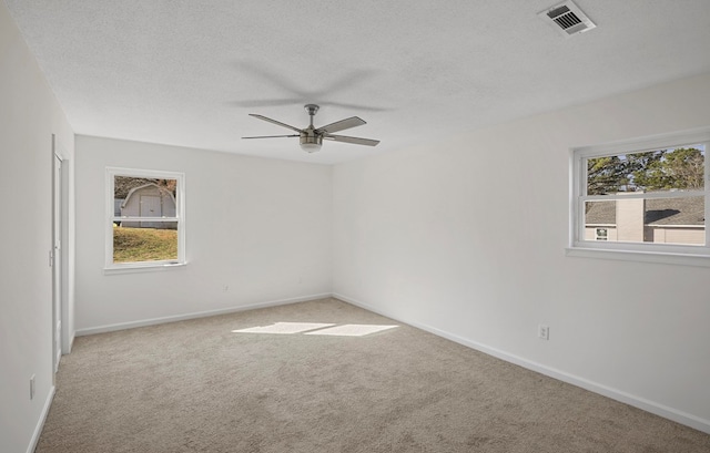 carpeted empty room featuring ceiling fan, a textured ceiling, and a healthy amount of sunlight