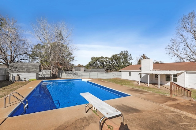 view of pool with a patio, a diving board, and a storage unit