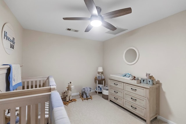 bedroom with ceiling fan, light carpet, and a nursery area