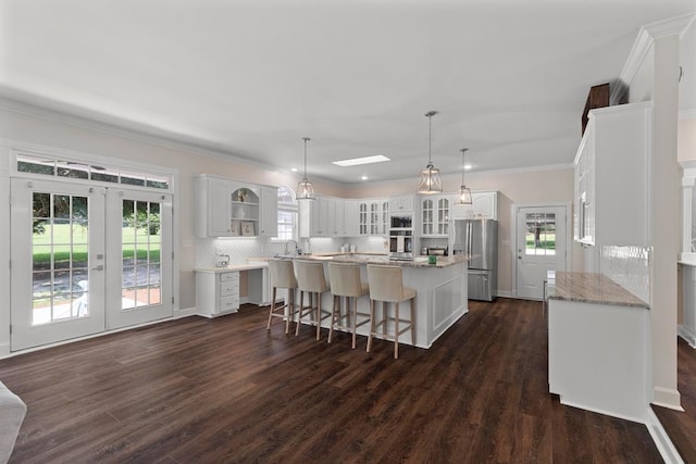 kitchen with white cabinetry, a wealth of natural light, a center island, and stainless steel fridge with ice dispenser