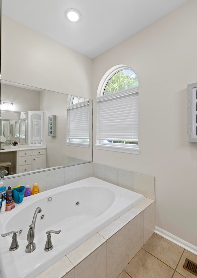 bathroom featuring tile patterned flooring, vanity, and tiled tub