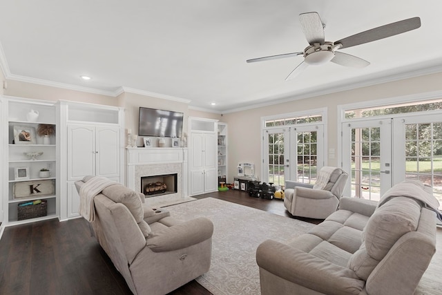 living room with ceiling fan, french doors, dark wood-type flooring, a premium fireplace, and crown molding