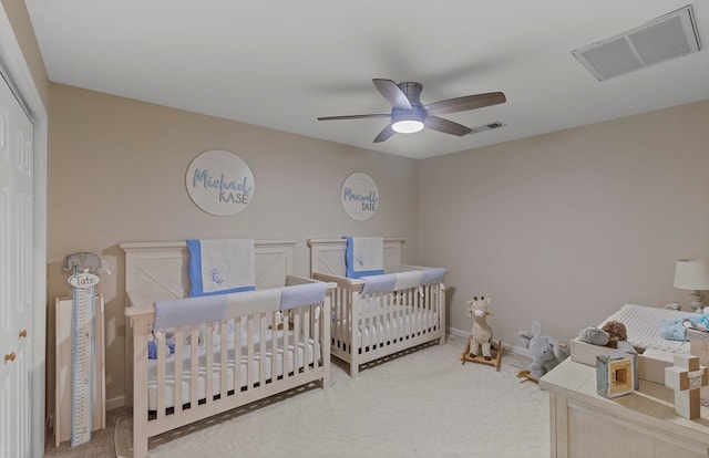 carpeted bedroom featuring ceiling fan, a closet, and a nursery area