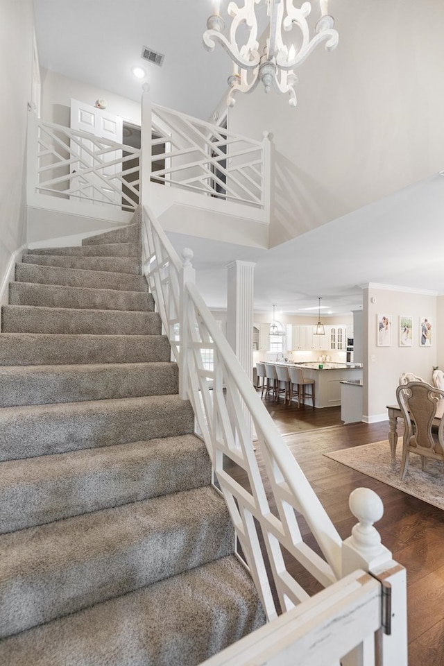 staircase with a high ceiling, a notable chandelier, and hardwood / wood-style flooring