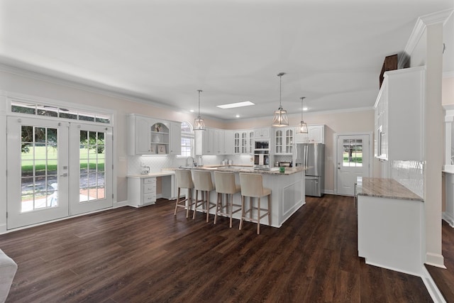 kitchen featuring white cabinetry, a wealth of natural light, stainless steel fridge, and a kitchen island