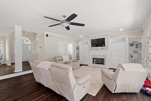 living room with crown molding, dark hardwood / wood-style flooring, ceiling fan, and a premium fireplace