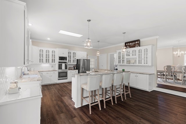 kitchen with backsplash, dark wood-type flooring, white cabinets, appliances with stainless steel finishes, and a kitchen island