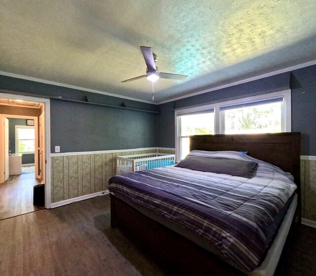 bedroom featuring hardwood / wood-style flooring, crown molding, ceiling fan, and a textured ceiling