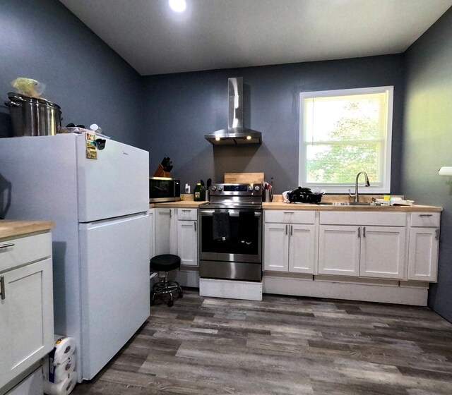 kitchen with white cabinetry, appliances with stainless steel finishes, sink, and wall chimney range hood