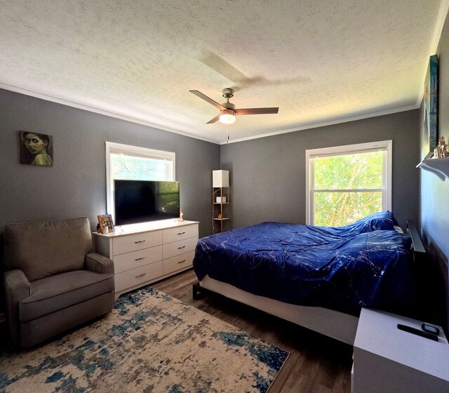 bedroom with crown molding, dark wood-type flooring, ceiling fan, and a textured ceiling