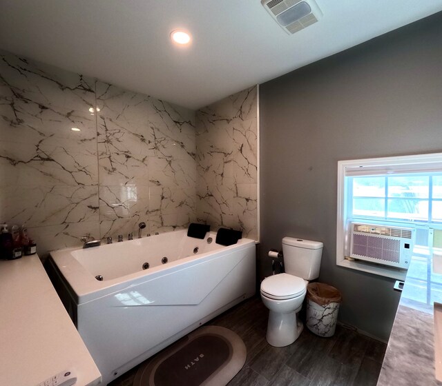 bathroom with hardwood / wood-style flooring, cooling unit, tile walls, a tub to relax in, and toilet