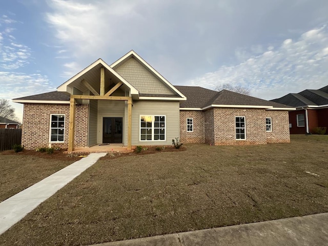 rear view of property with a lawn, brick siding, and a shingled roof