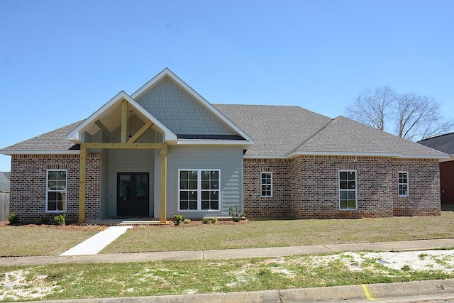 view of front of home with brick siding, a front lawn, and roof with shingles