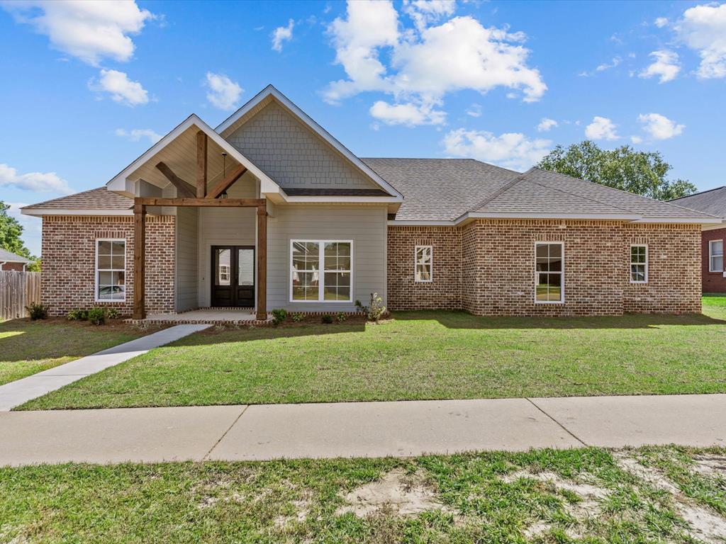view of front facade with fence, a shingled roof, a front lawn, french doors, and brick siding