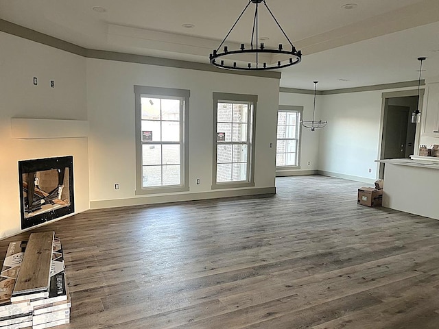 unfurnished living room with dark wood-style floors, a notable chandelier, and baseboards