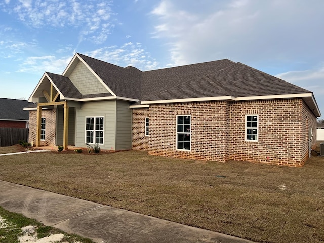 view of side of property featuring a lawn, brick siding, and a shingled roof