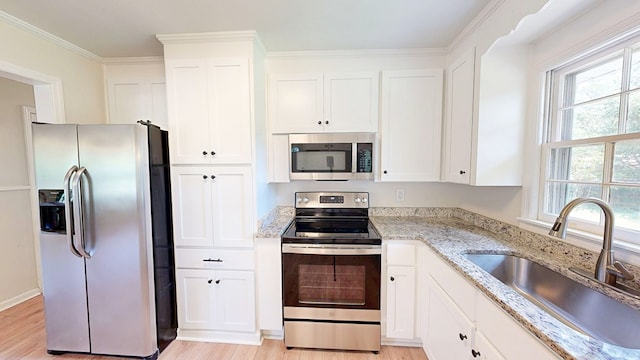 1007 Deborah St, Dothan, AL 36301 - kitchen featuring appliances with stainless steel finishes, light wood-style floors, white cabinetry, and crown molding
