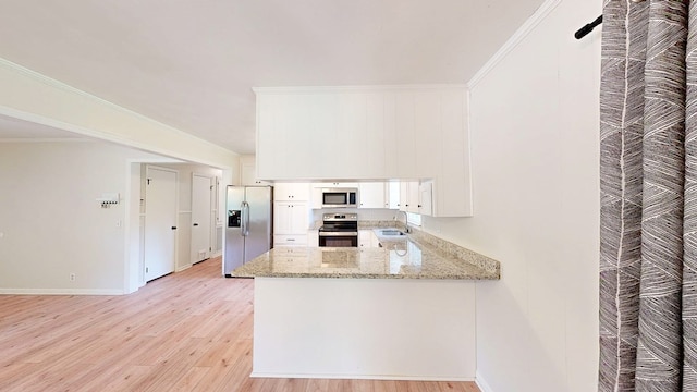 1007 Deborah St, Dothan, AL 36301 - kitchen featuring appliances with stainless steel finishes, light wood finished floors, a peninsula, white cabinets, and light stone counters