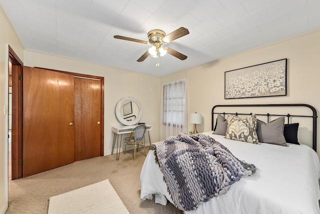 carpeted bedroom with ceiling fan, crown molding, and a closet