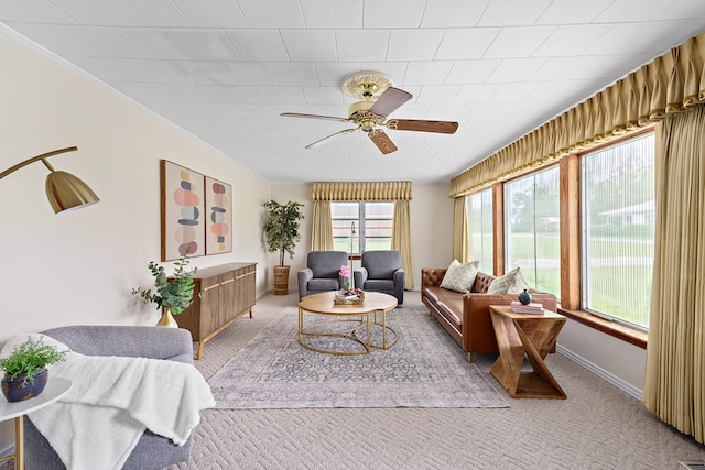 carpeted living room featuring ceiling fan and ornamental molding