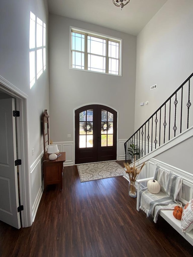 entryway featuring dark wood-type flooring, french doors, a healthy amount of sunlight, and a high ceiling