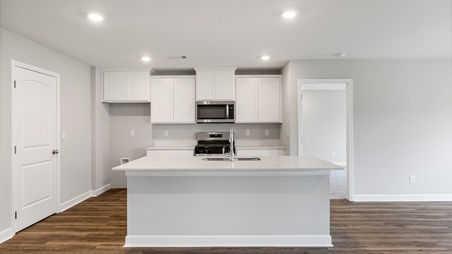 kitchen with dark wood-style flooring, a kitchen island with sink, stainless steel appliances, white cabinetry, and a sink