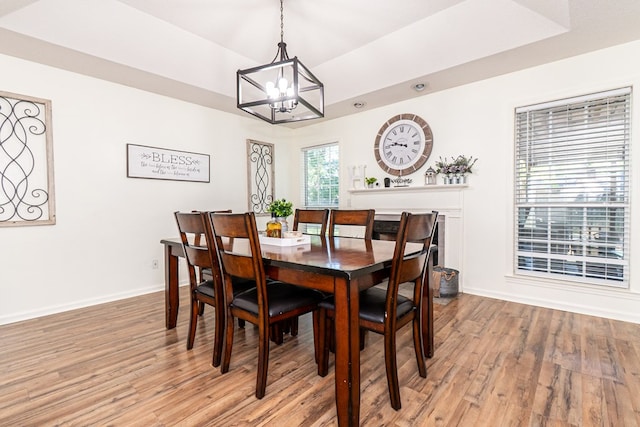 dining area with light wood-style flooring, baseboards, and an inviting chandelier