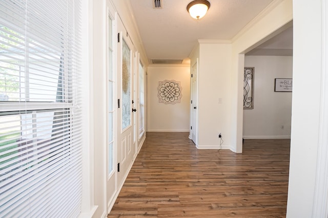 hallway with visible vents, baseboards, wood finished floors, and crown molding