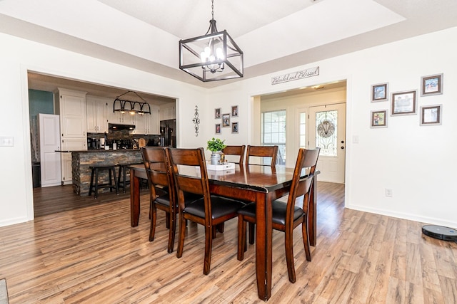 dining area with baseboards, a chandelier, and light wood-type flooring