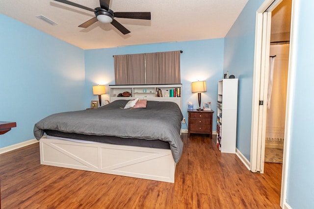 bedroom with wood finished floors, visible vents, baseboards, and ceiling fan