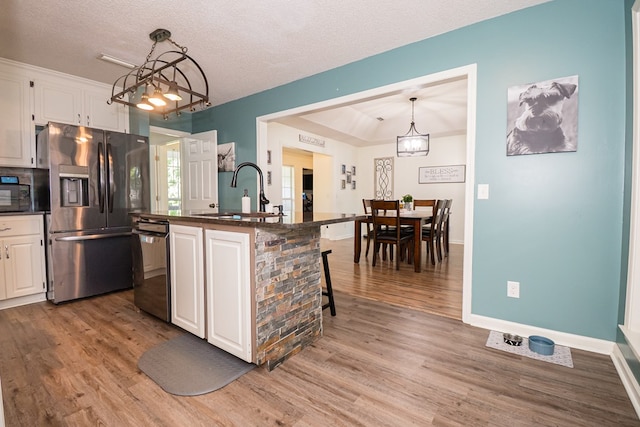 kitchen featuring stainless steel refrigerator with ice dispenser, dishwashing machine, a sink, and a notable chandelier