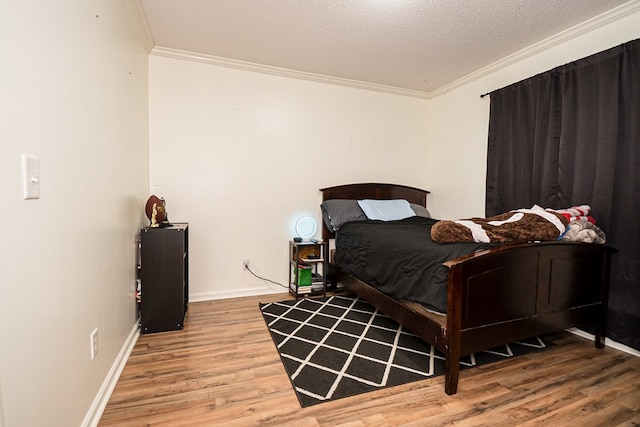 bedroom with wood finished floors, a textured ceiling, baseboards, and ornamental molding