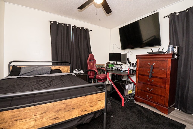 bedroom with a ceiling fan, wood finished floors, and a textured ceiling