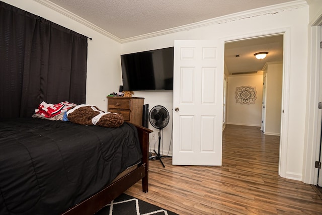 bedroom with wood finished floors, a textured ceiling, and ornamental molding